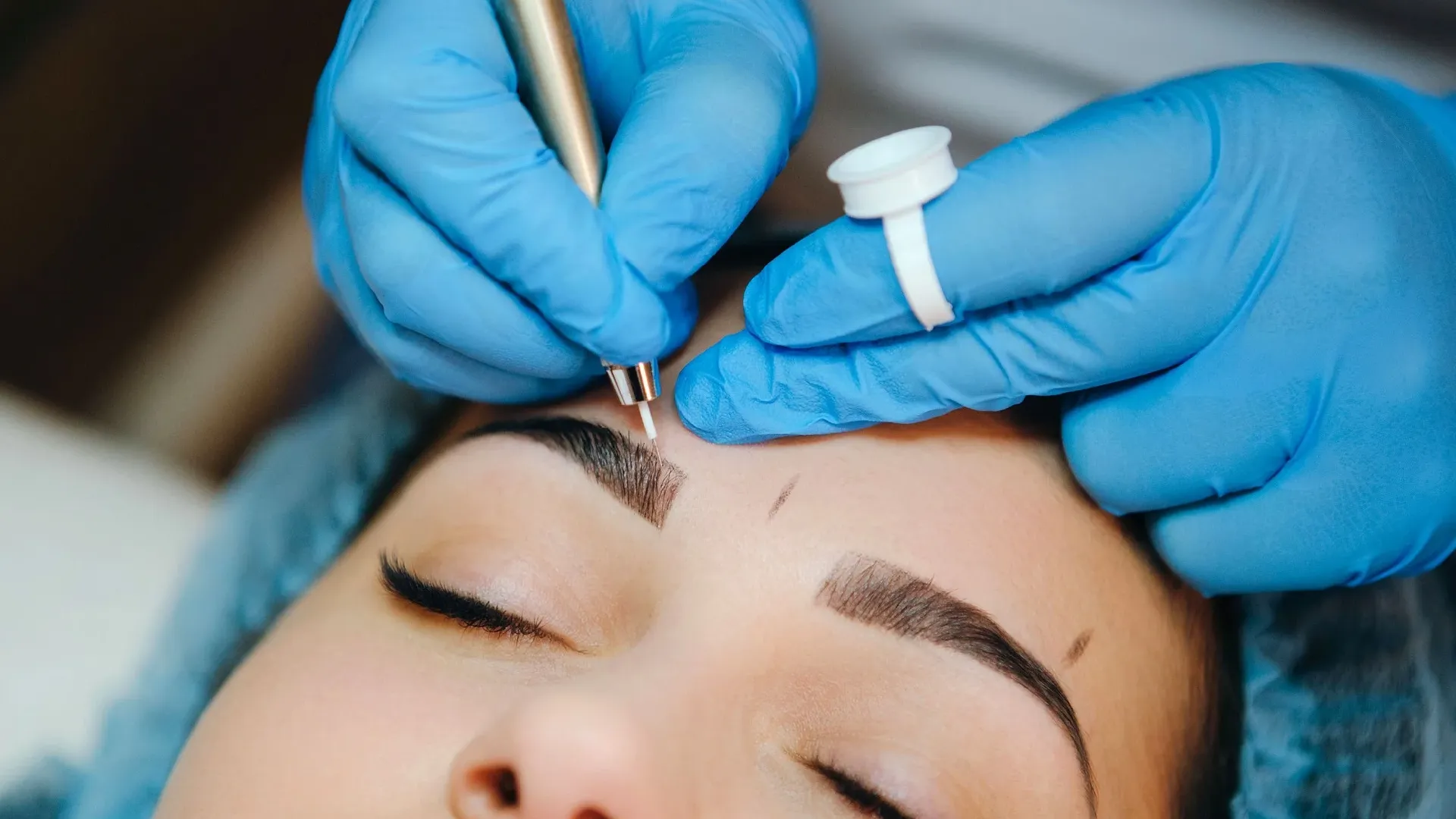 Close-up of a client receiving eyebrow treatments, enhancing brow shape.