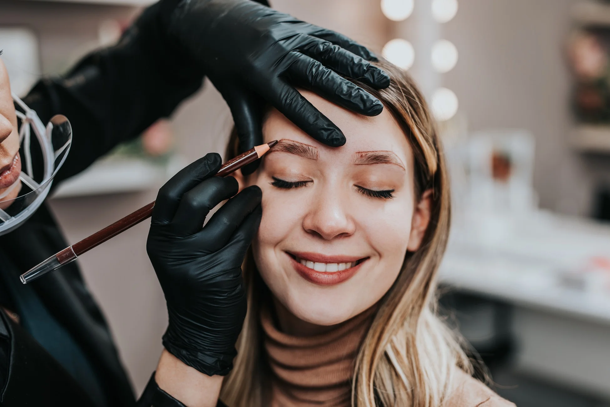 A smiling woman receiving expert eyebrow services.