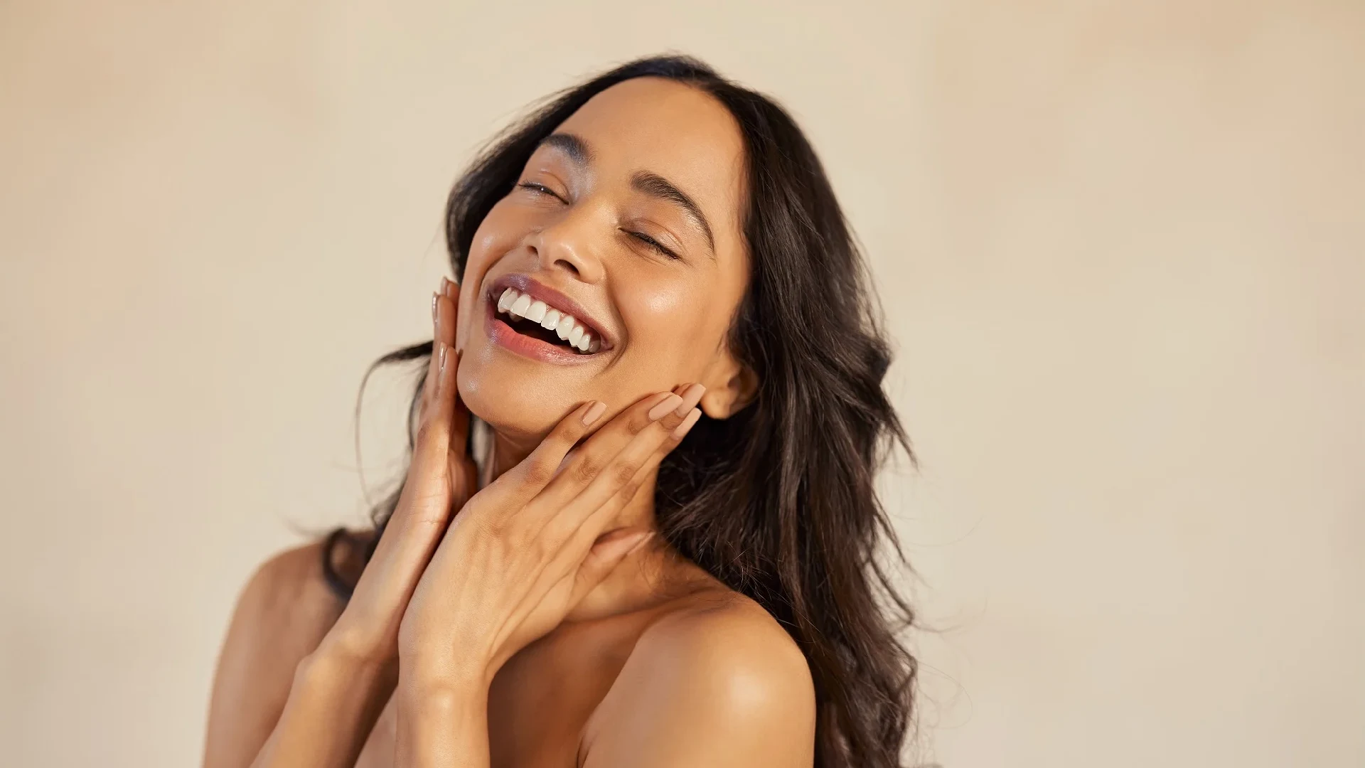 A happy woman touching her radiant skin, highlighting effective skin tightening services