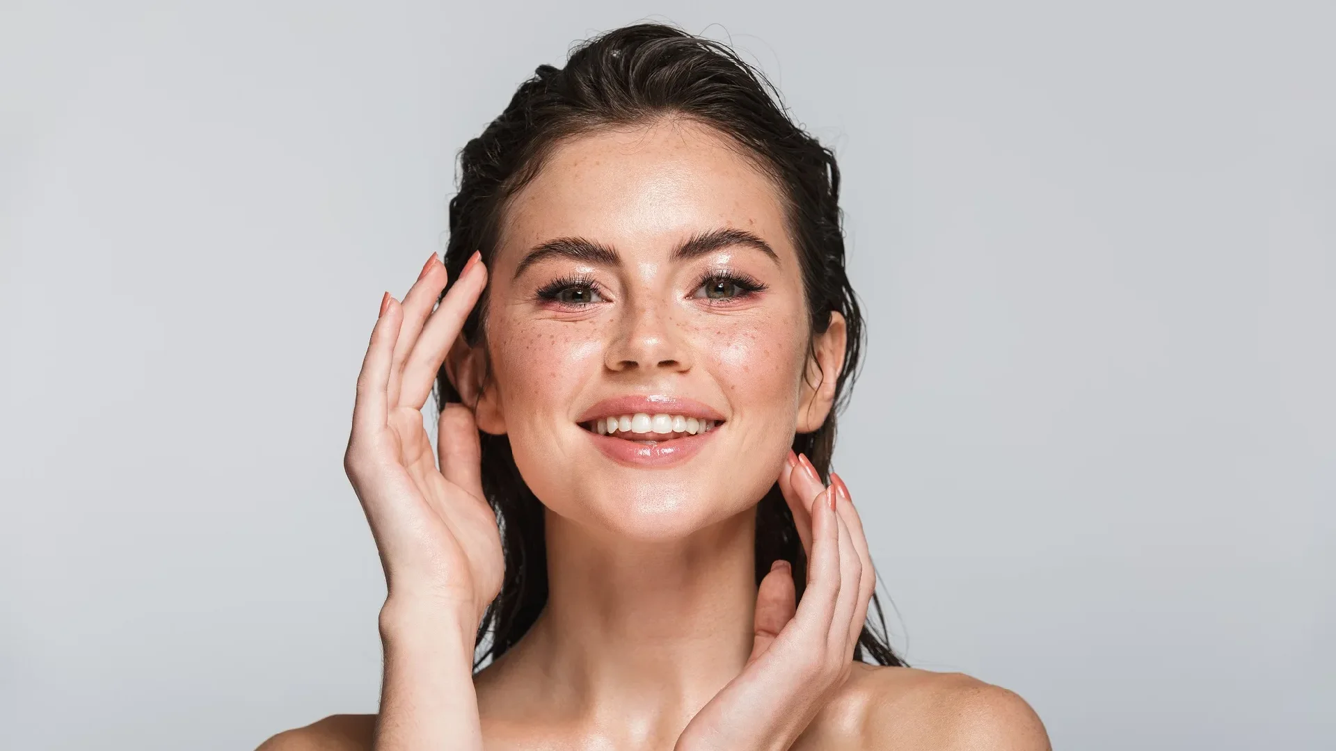 A smiling woman admiring her face after a microchanneling treatment.