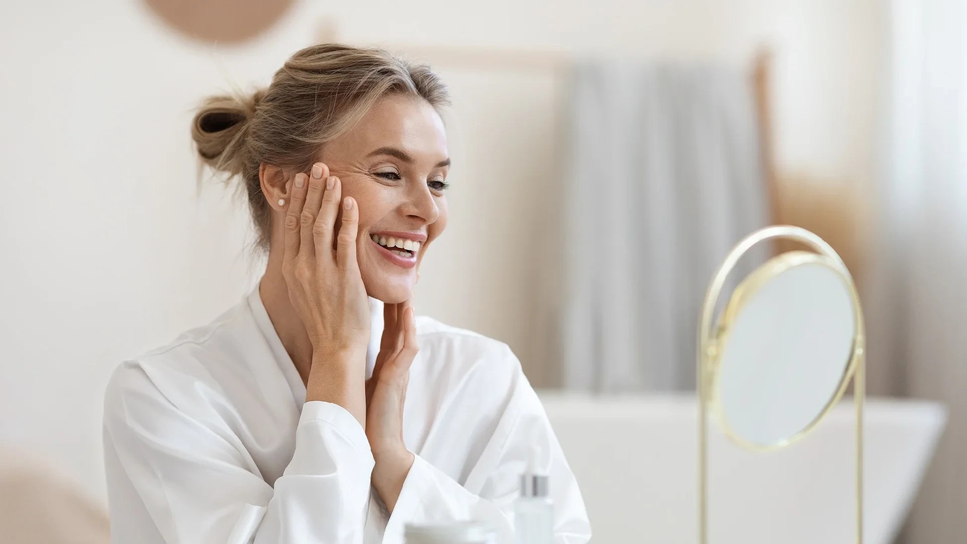 A radiant woman smiling and touching her face, showcasing effective skincare services.