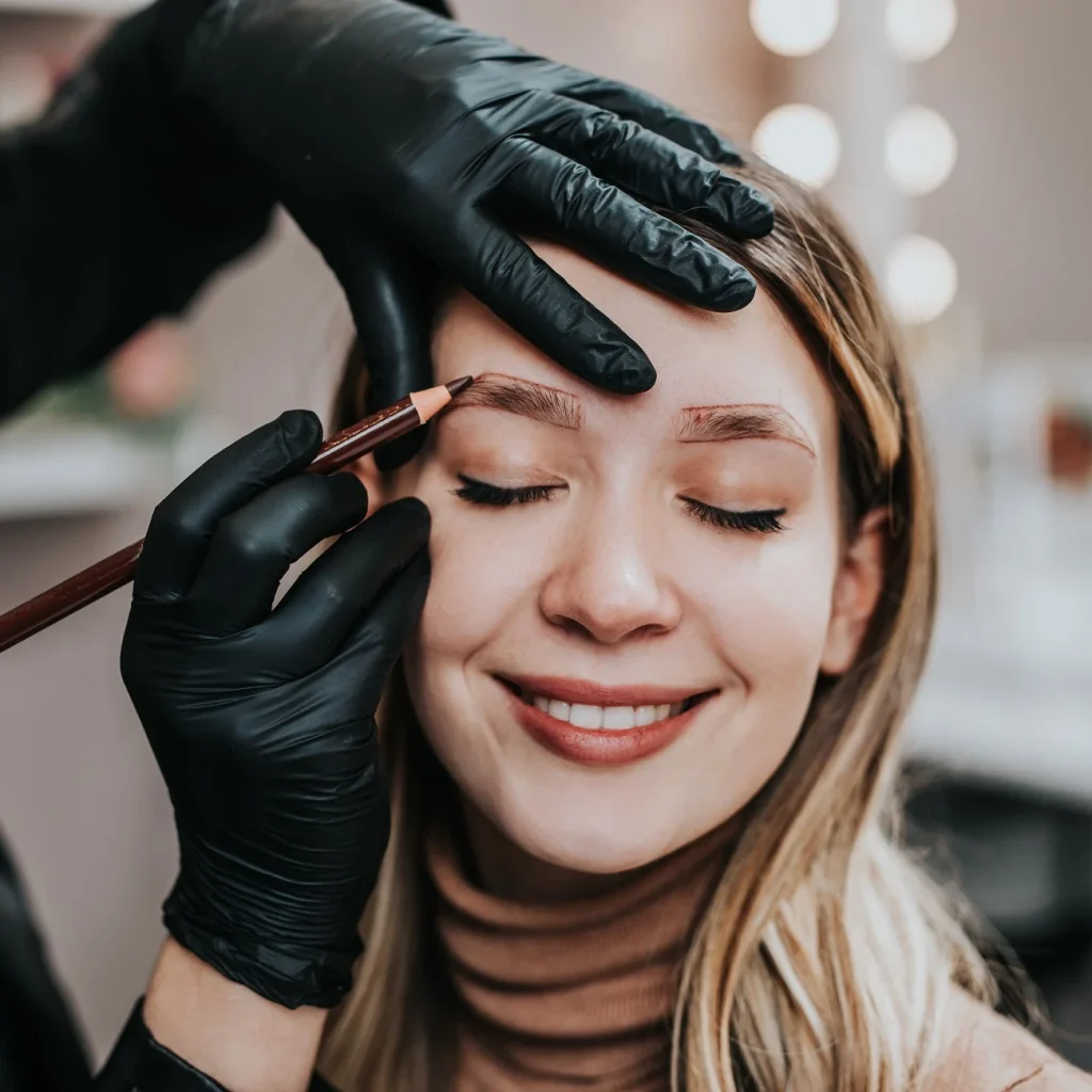 A smiling woman receiving expert eyebrow services.