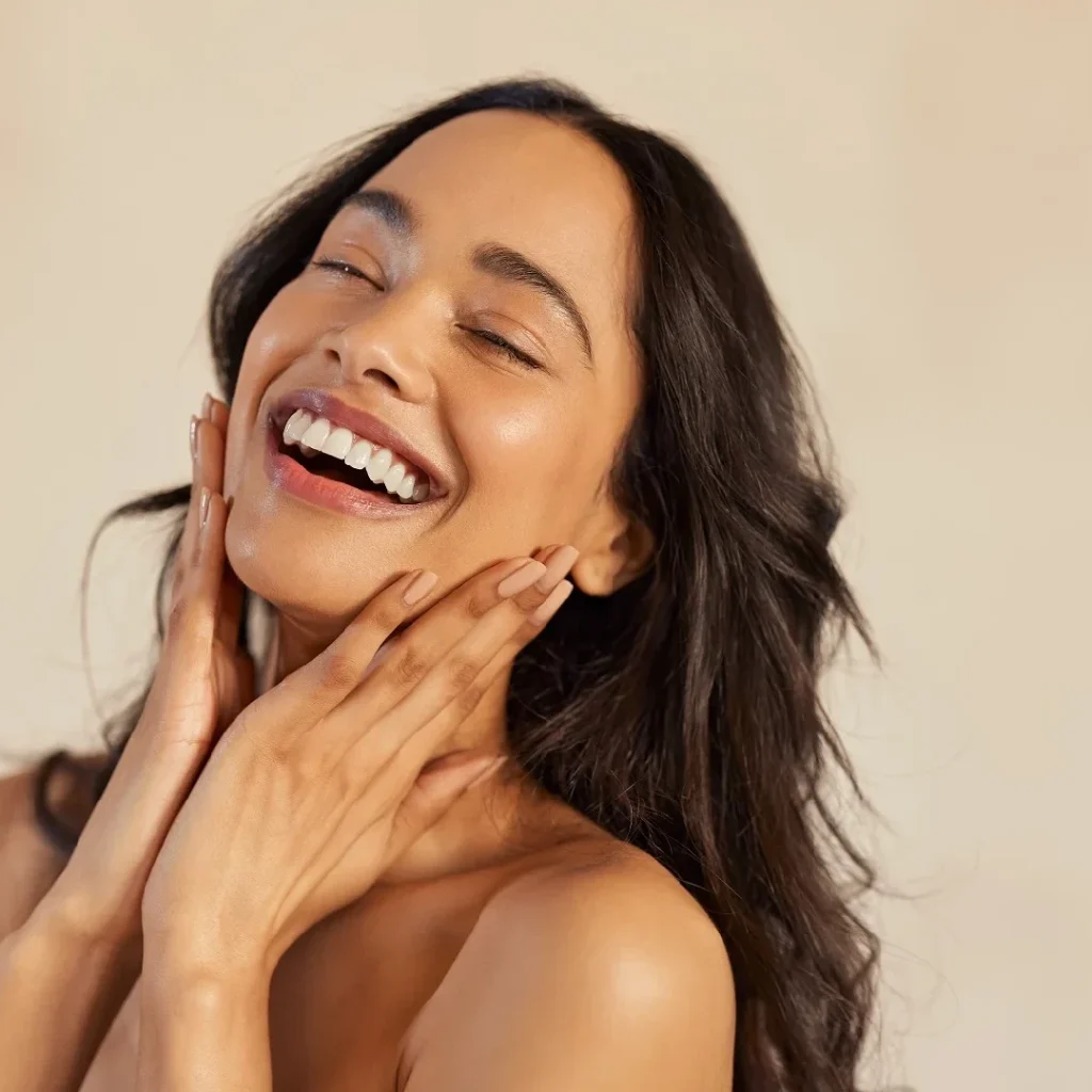 A happy woman touching her radiant skin, highlighting effective skin tightening services
