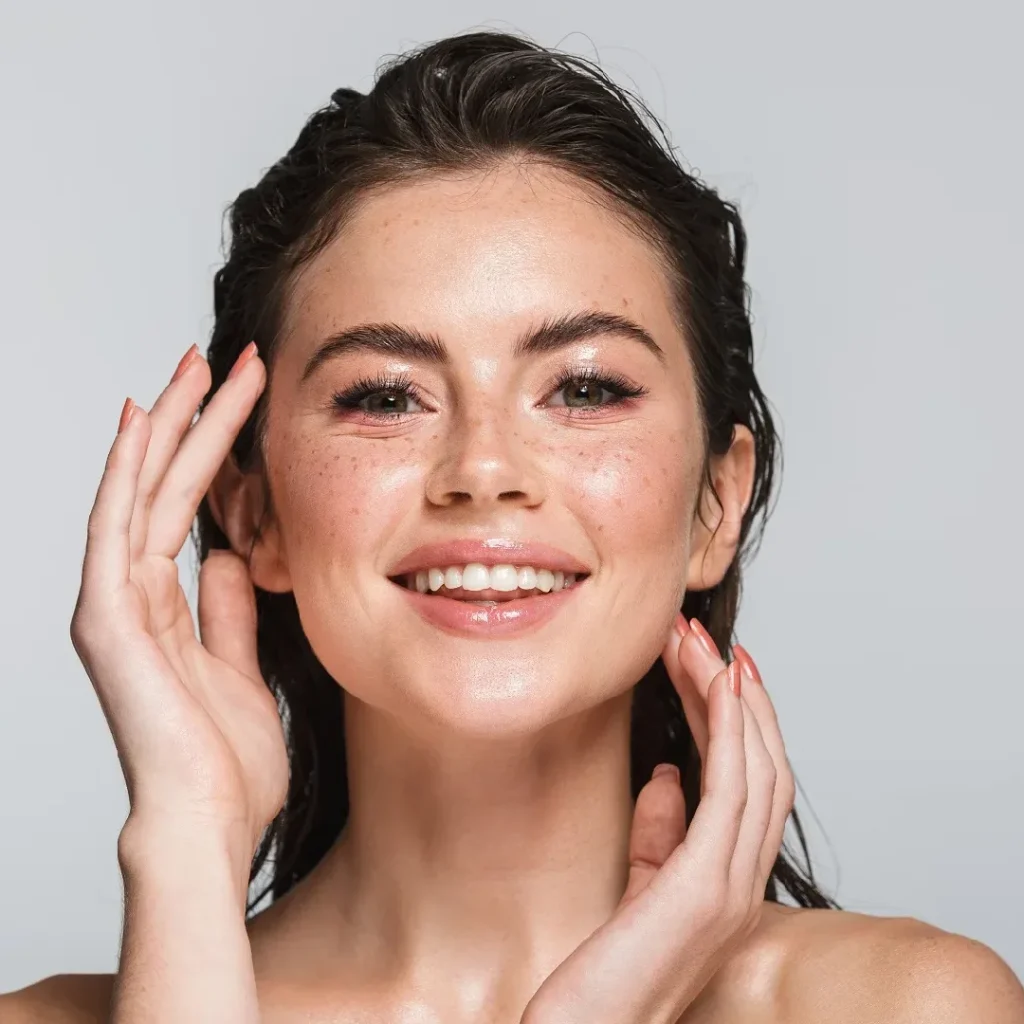 A smiling woman admiring her face after a microchanneling treatment.