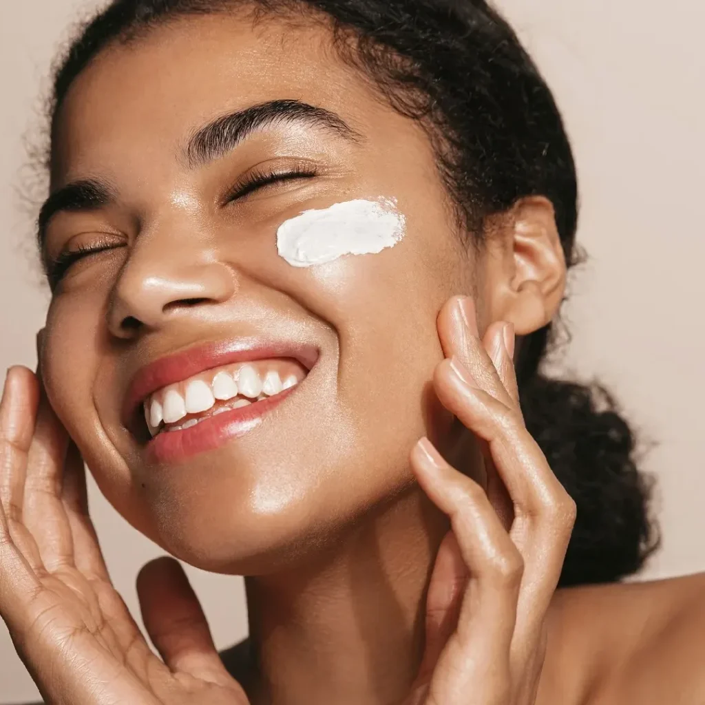 A joyful woman with Osmosis Skincare cream on her cheek.