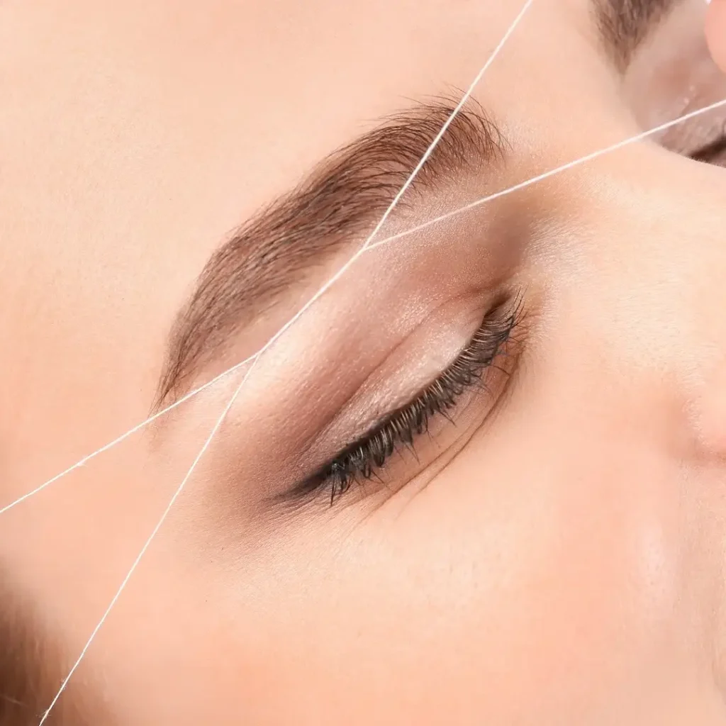 Close-up of a woman receiving threading services for her eyebrows.
